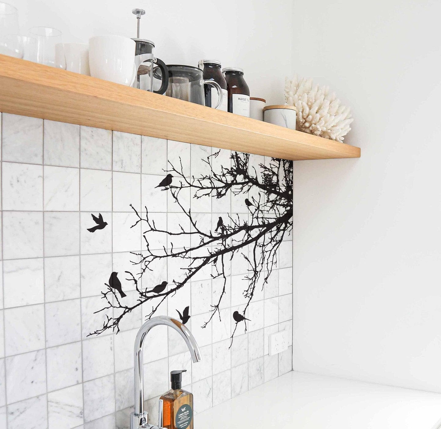 Black decal of 8 birds on tree branches on a white wall near a kitchen sink.