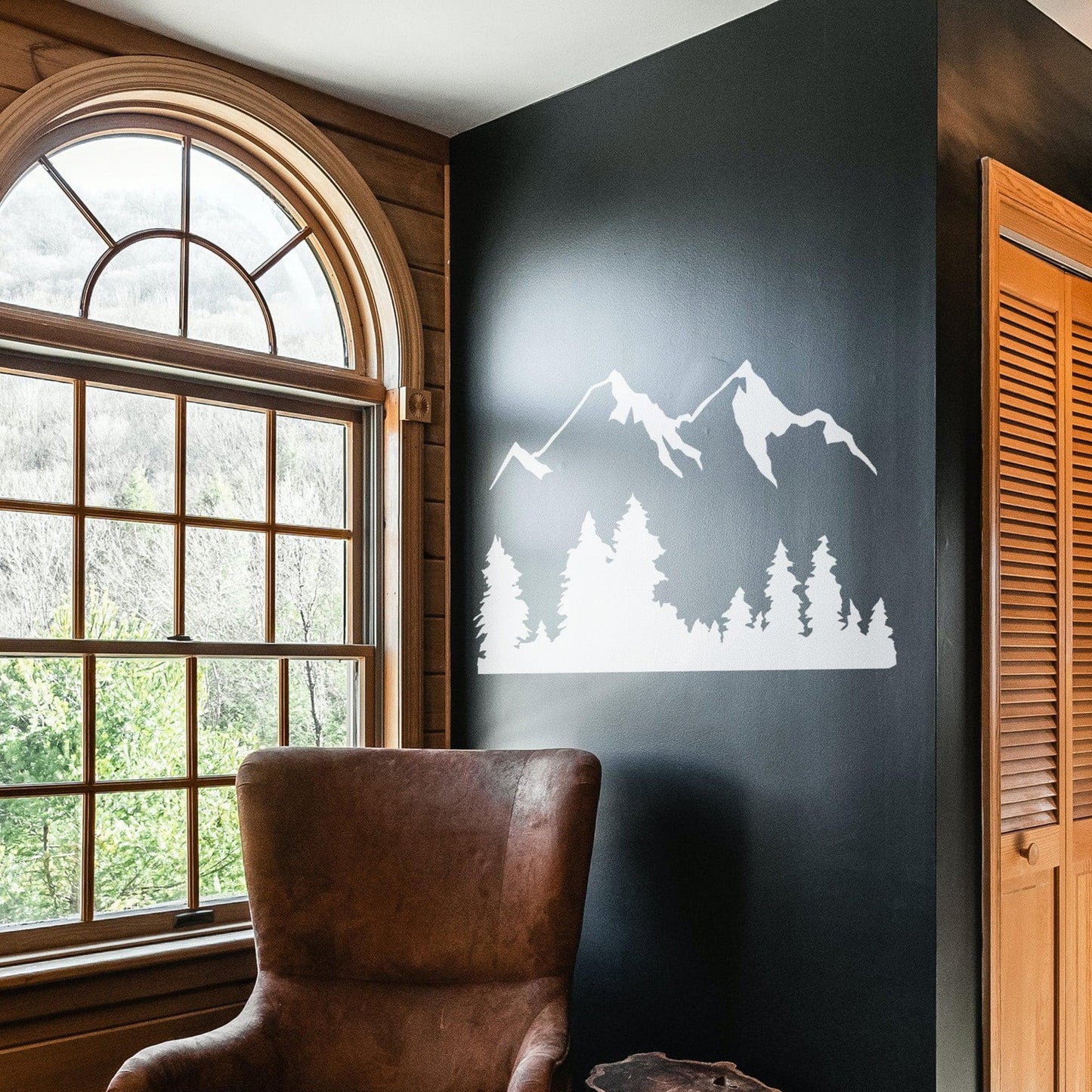 White mountain decal on a black wall above an armchair.