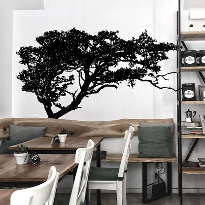 Black tree decal on a white wall above a wooden bench.