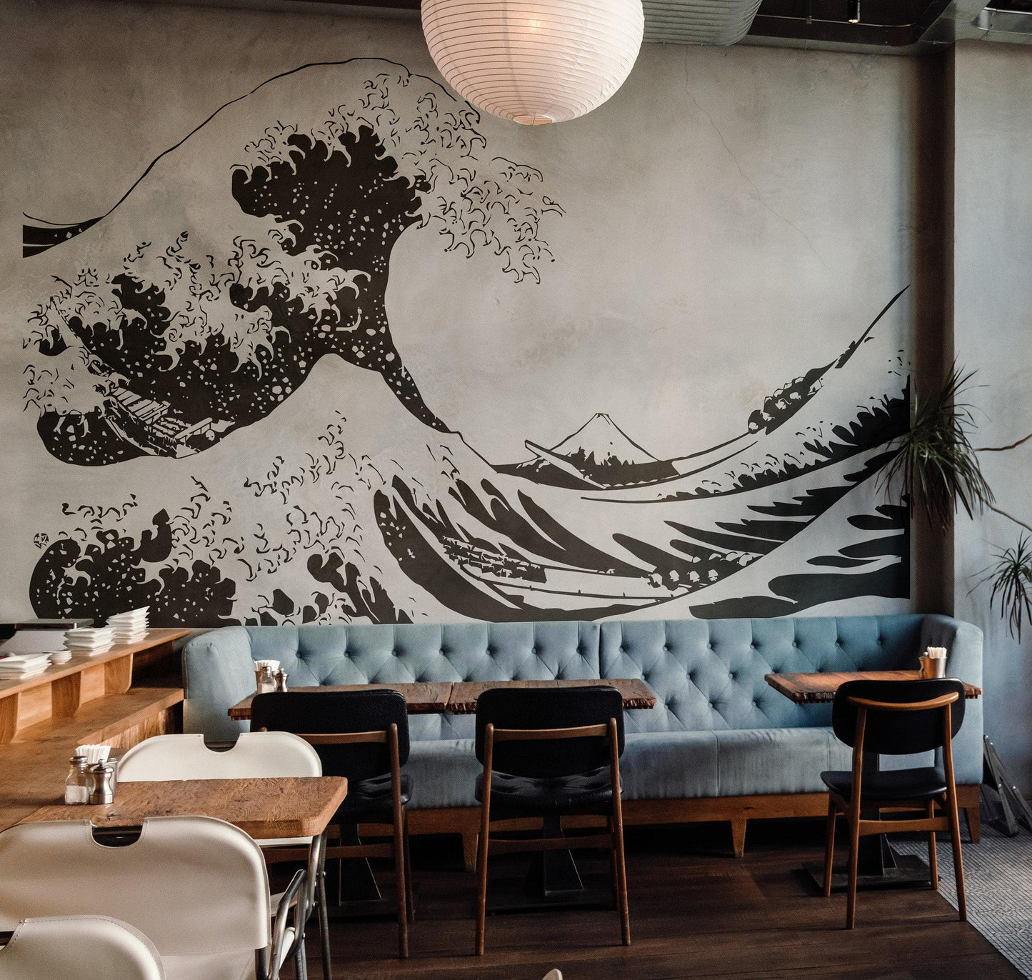 The Great Wave wall decal on a gray wall above a blue couch in a cafe