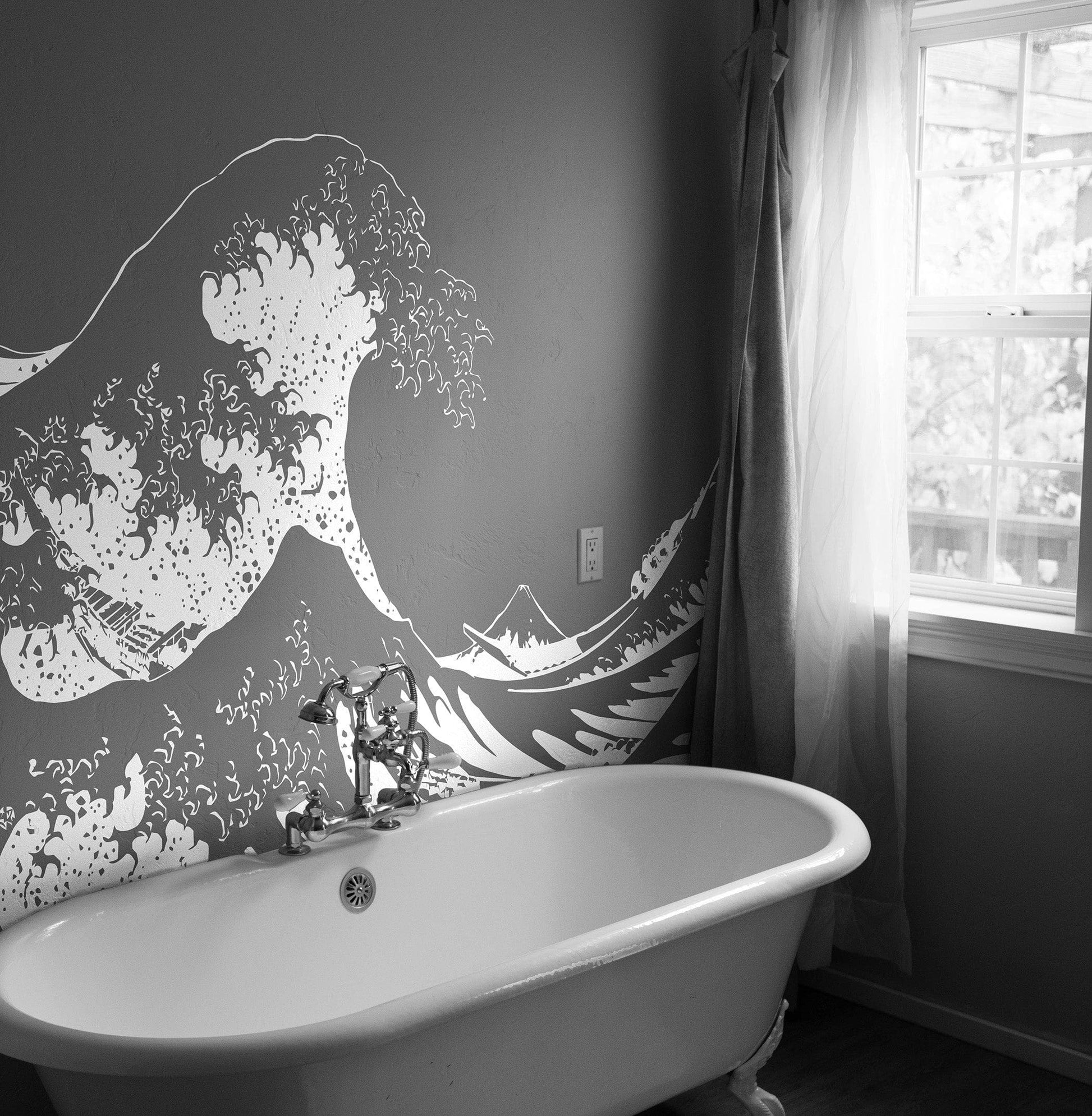 The Great Wave wall decal on a dark gray wall above a white tub.