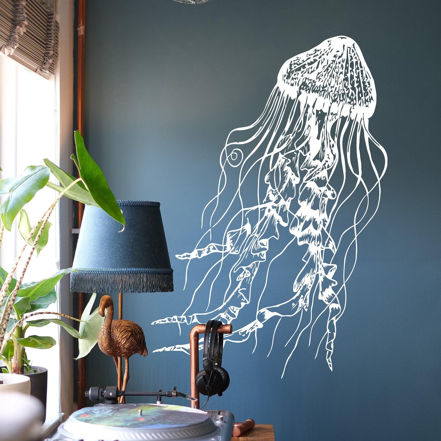 White jellyfish wall decal on a dark blue wall near a blue lamp.