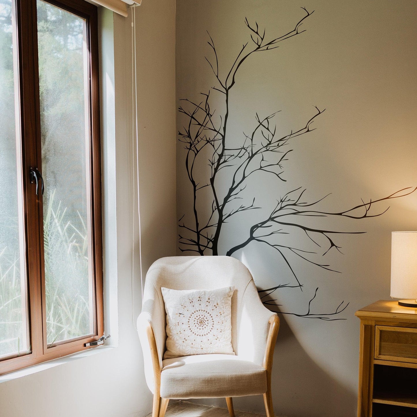 A black tree decal on a white wall in a living room above a white chair.