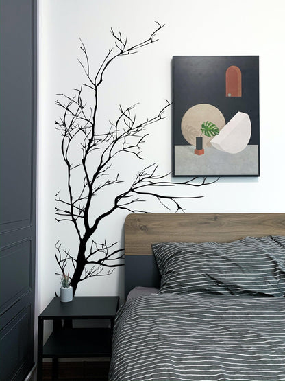 A black tree decal on a white wall in a bedroom.