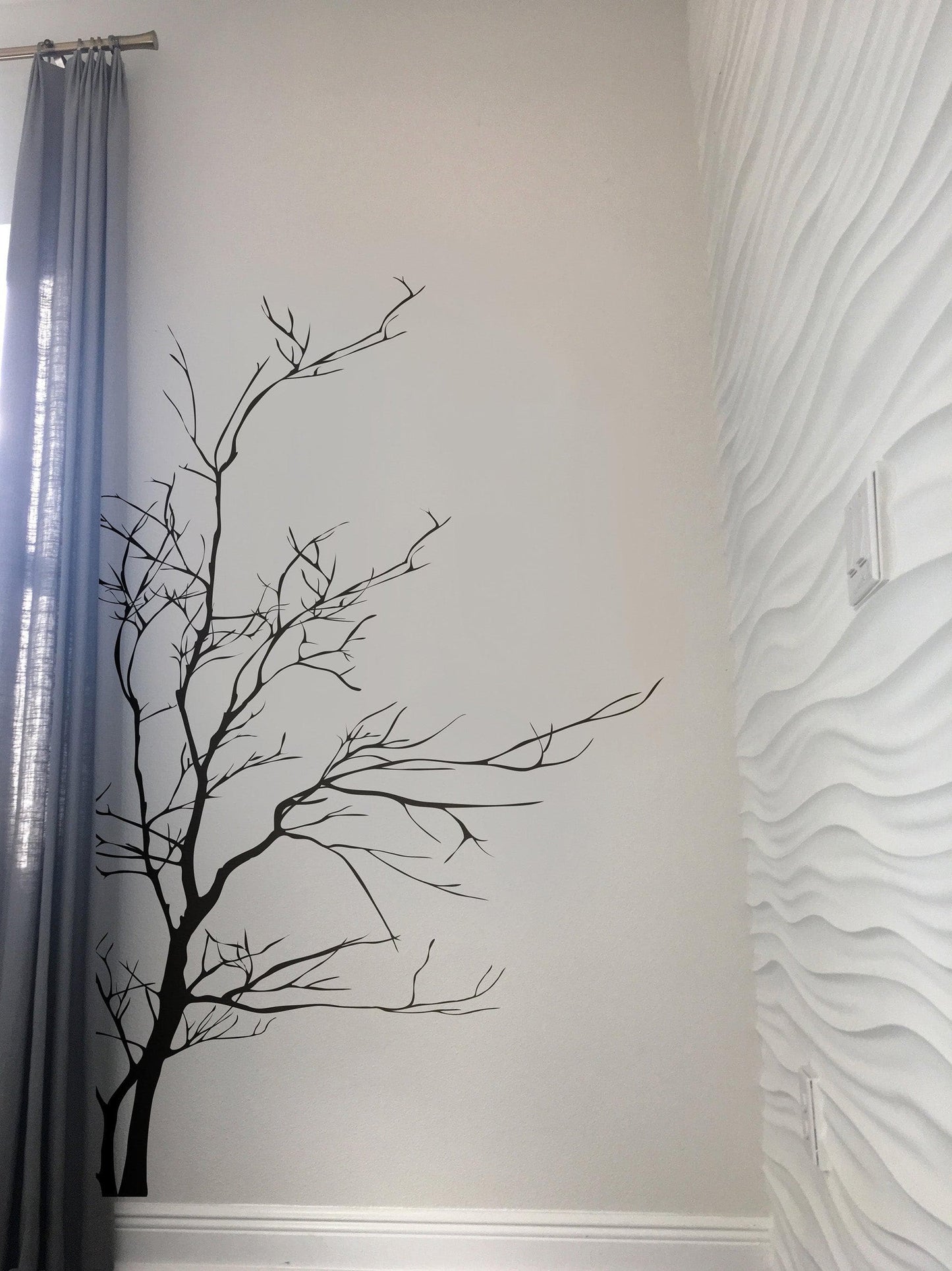 A black tree decal on a white wall in a bedroom.