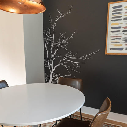 A white tree decal on a dark wall in a dining room.