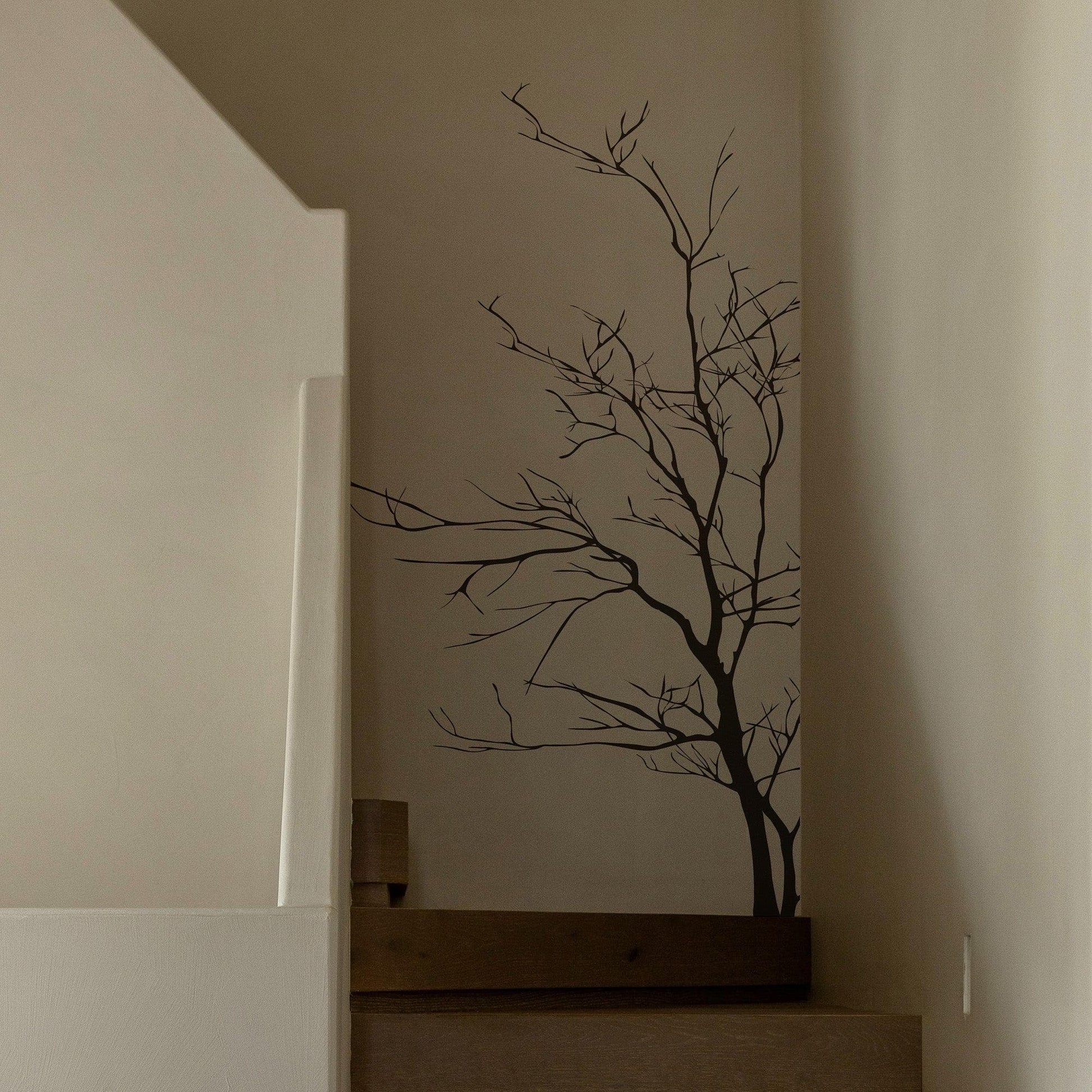 A black tree decal on a white wall near a staircase.