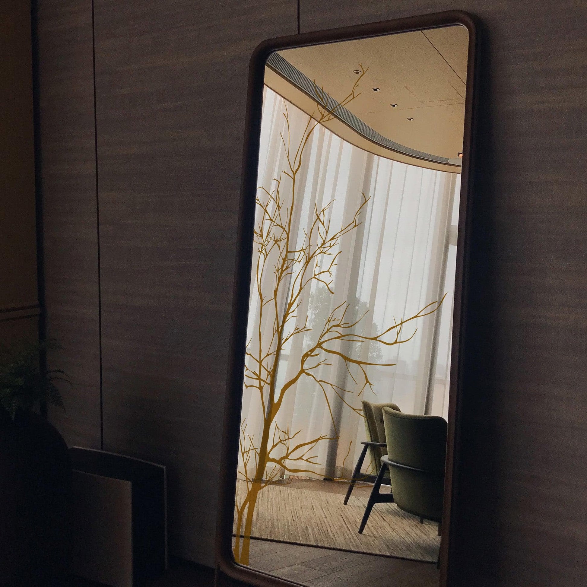 A gold tree decal on a mirror surface in a living room.