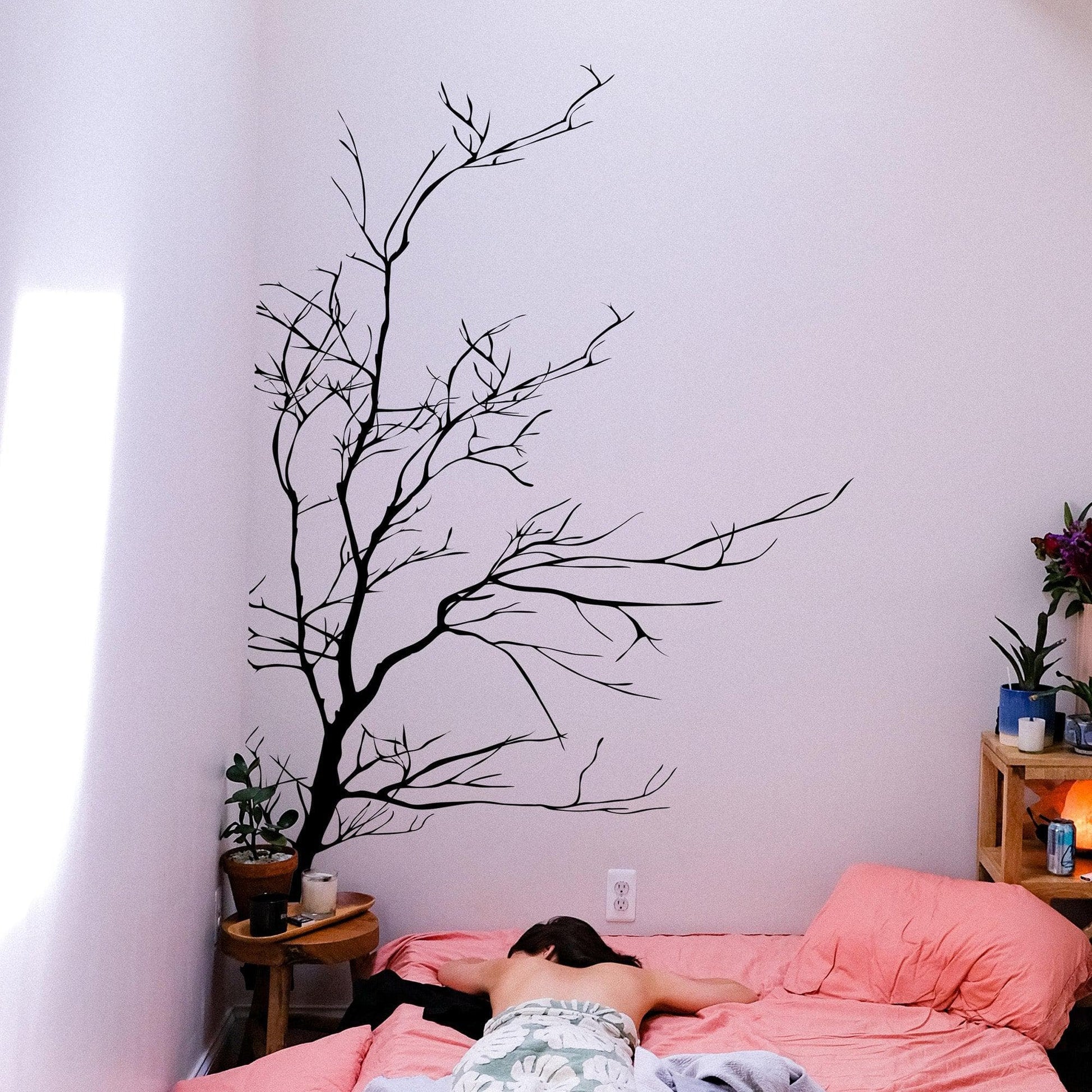 A black tree decal on a white wall in a bedroom. 