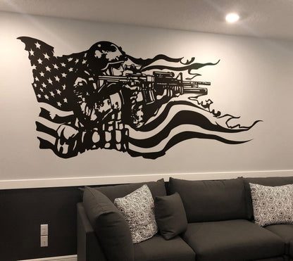 A black decal on a white wall showing a soldier holding a gun and the American flag behind it. Underneath it is a black couch.