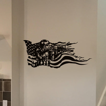 A black decal on a white wall showing a soldier holding a gun and the American flag behind it. 