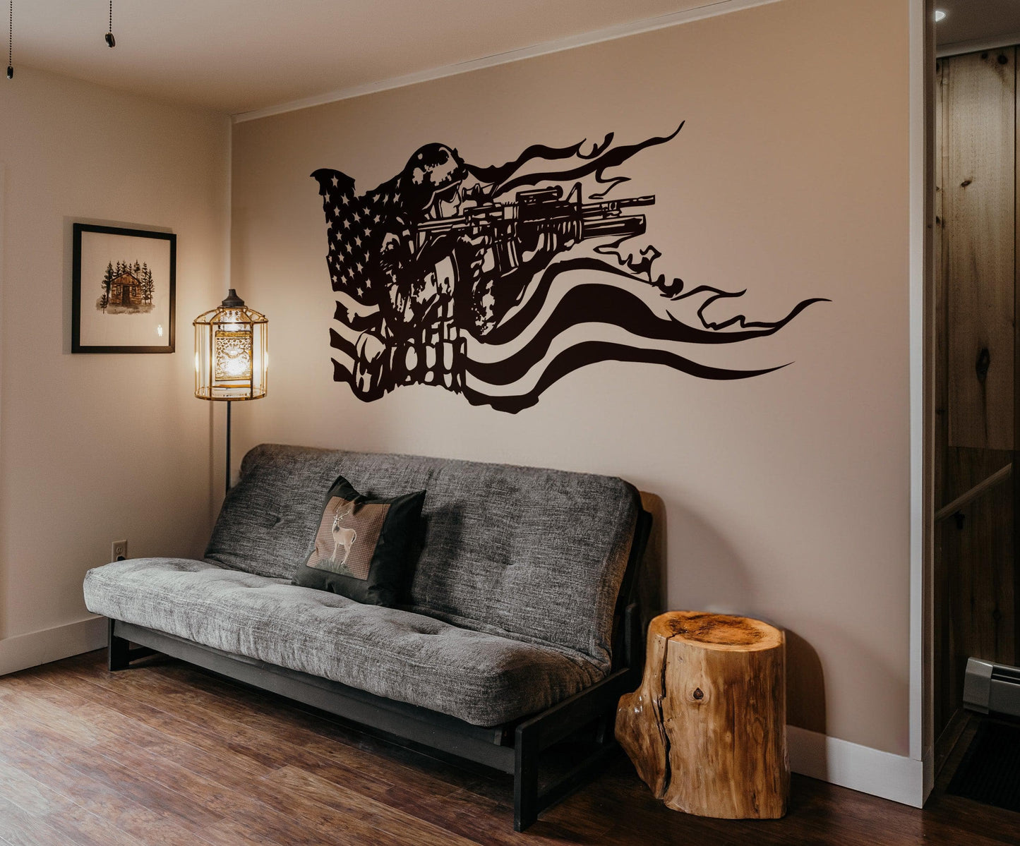 A black decal on a white wall showing a soldier holding a gun and the American flag behind it. Underneath it is a black couch.