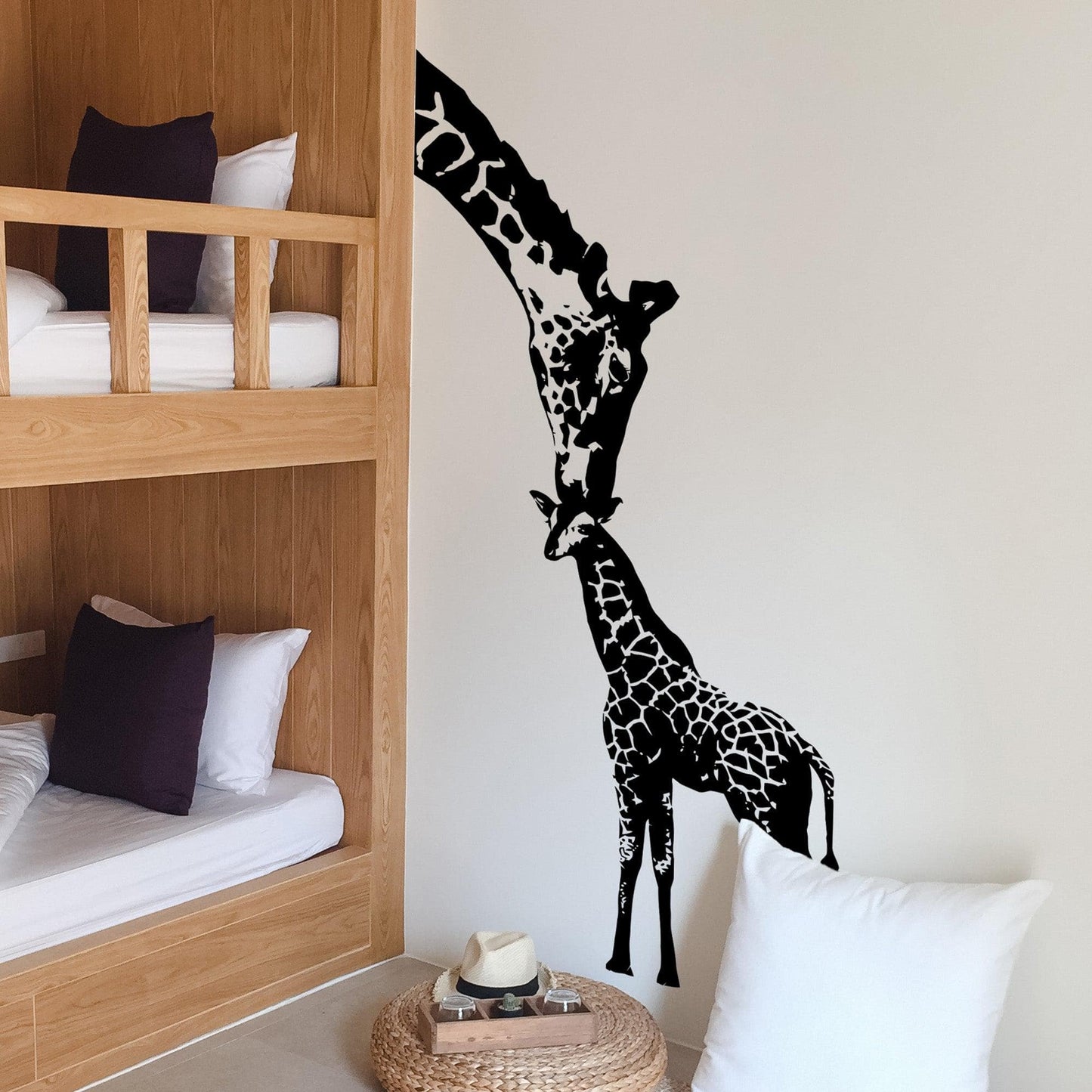 A black adult giraffe and a young giraffe decal on a white wall in a bedroom.