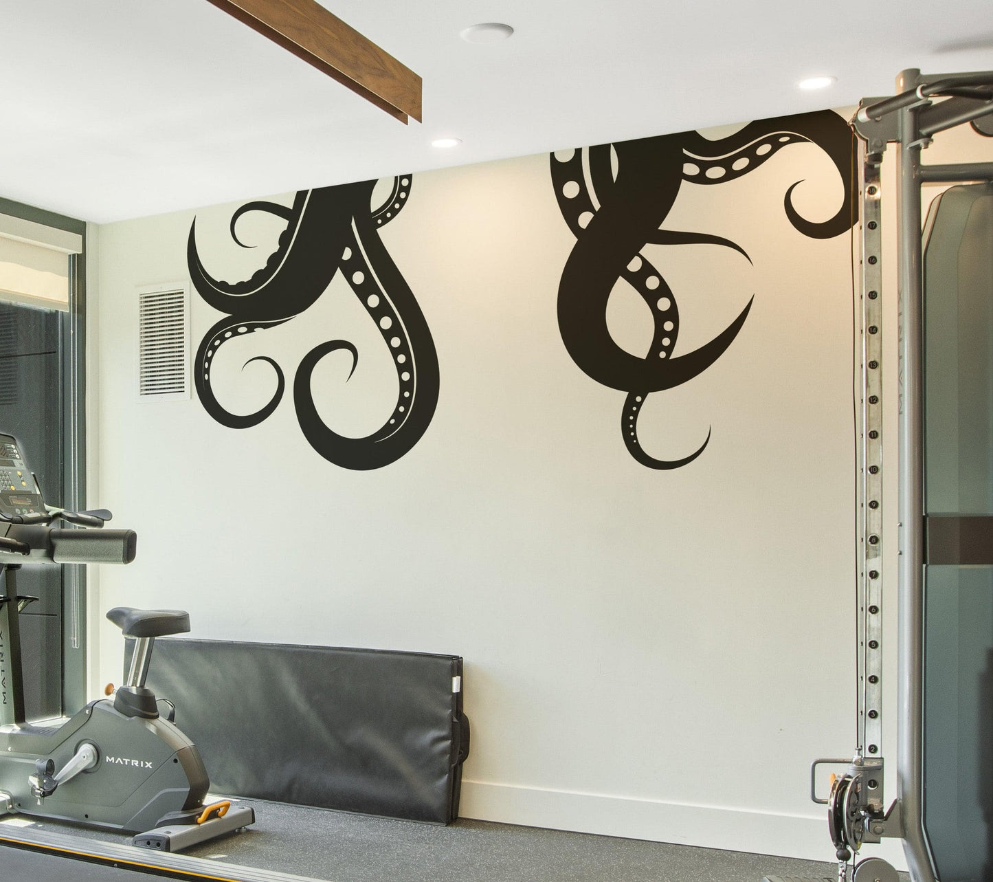 A black octopus tentacles decal on a white wall in a gym door.