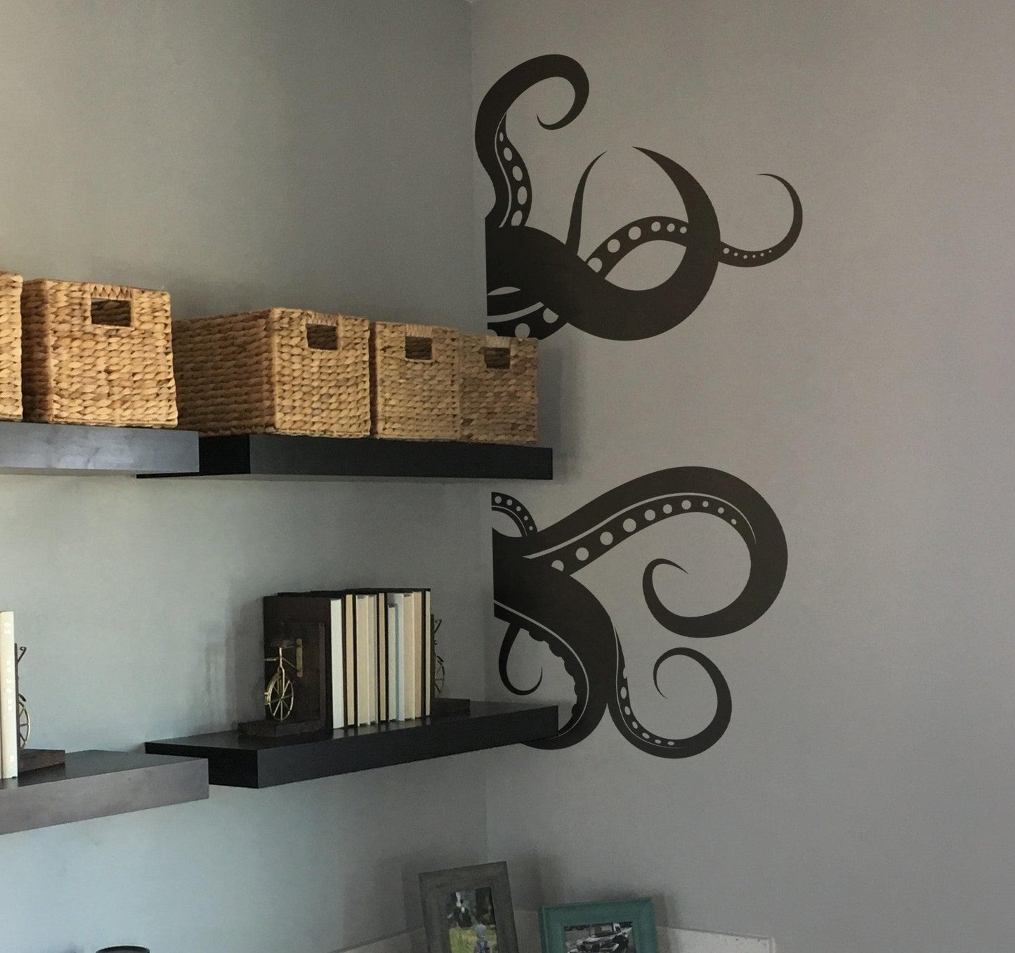 Black octopus tentacles decal on a white wall near a shelf.