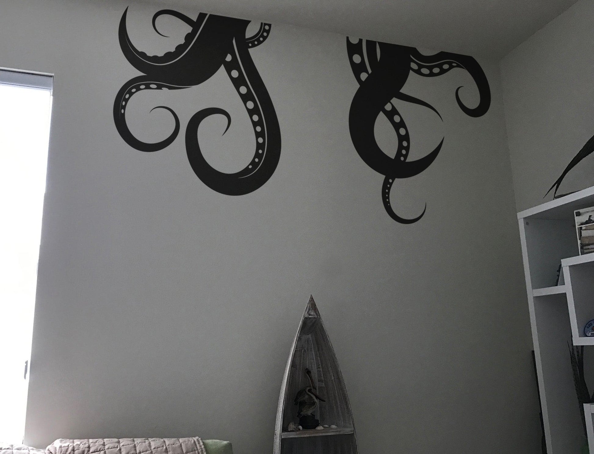 Black octopus tentacles decal on a white wall in a bedroom.