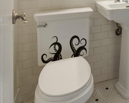 A black octopus tentacle decal on a white toilet in a bathroom.