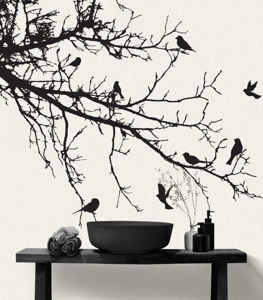 Black decal of 8 birds on tree branches on a white wall above a black sink, towels, and bottles.