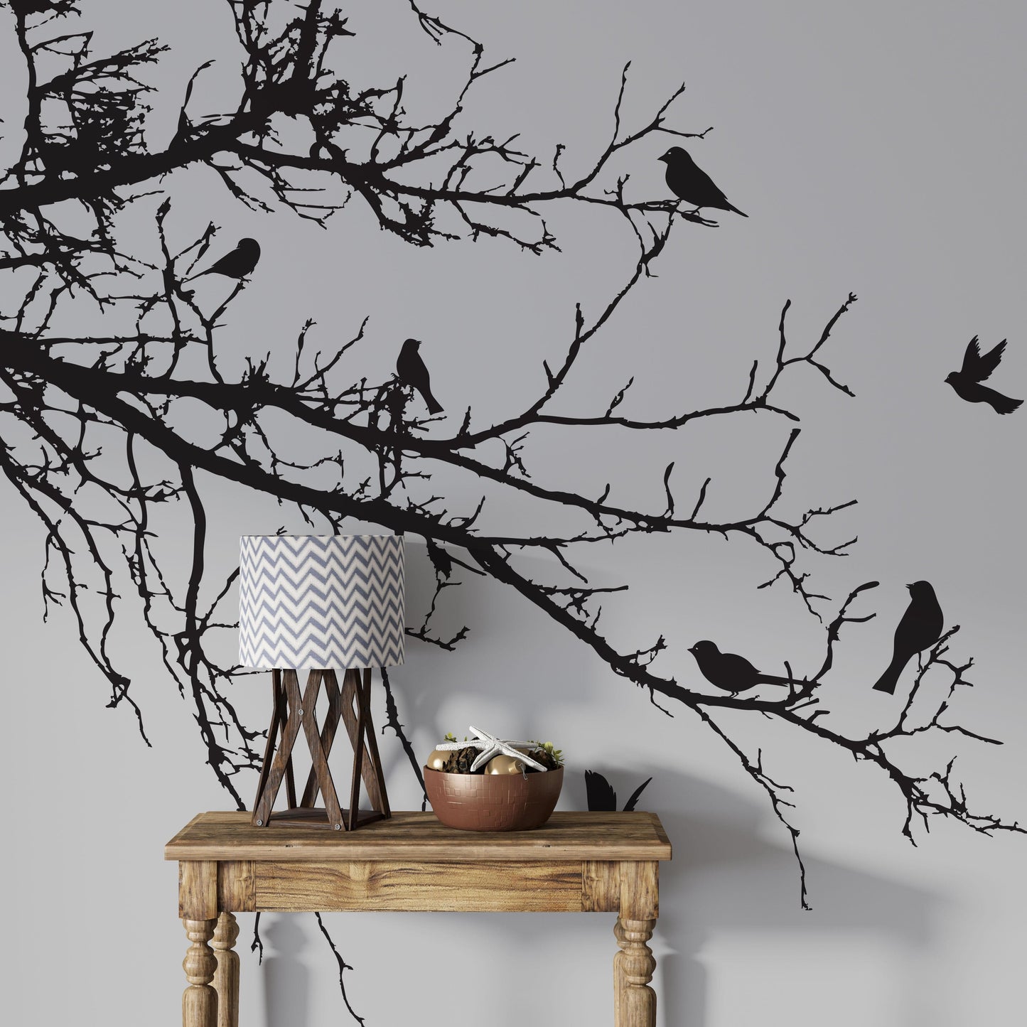 Black decal of 8 birds on tree branches on a white wall above a brown table.