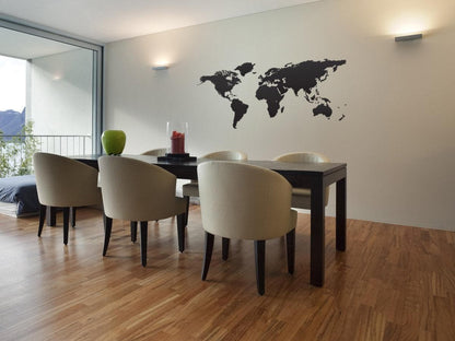 Black world map decal on a white wall in a dining room. 