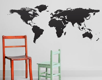 Gray world map decal on a white wall above red and green chairs.