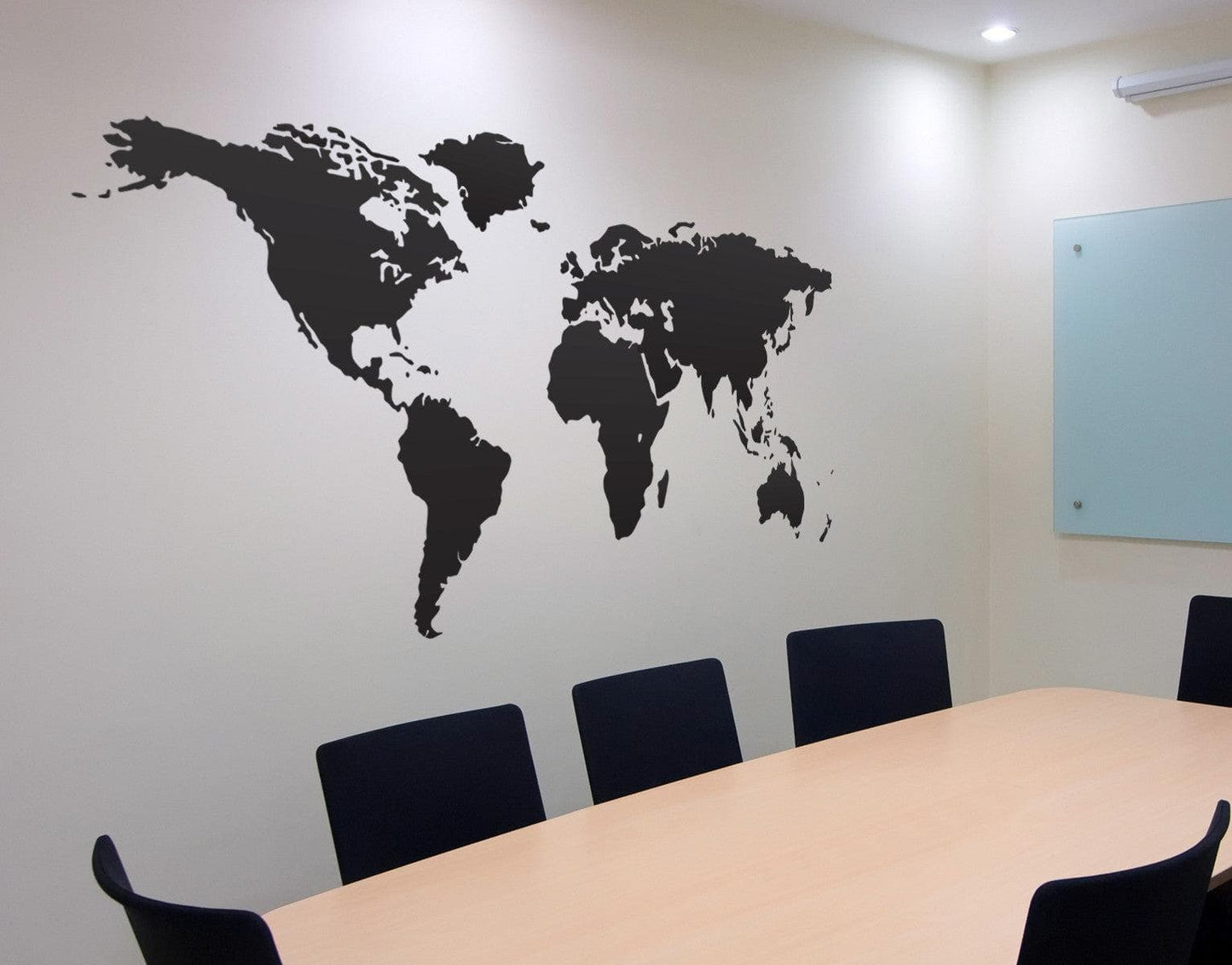 Black world map decal on a white wall in an office. 