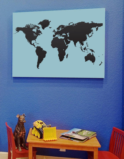 Black world map on a light blue wall above a table and red chairs.