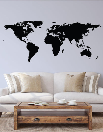 Black world map decal on a white wall above a white couch.