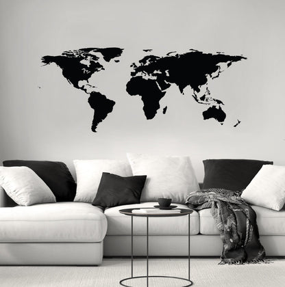Black world map decal on a white wall above a black and white couch.