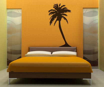 Black palm tree decals on a yellow wall above a bed.