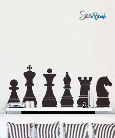 A black decal showing 6 chess pieces on a white wall above a white couch with 4 striped pillows.