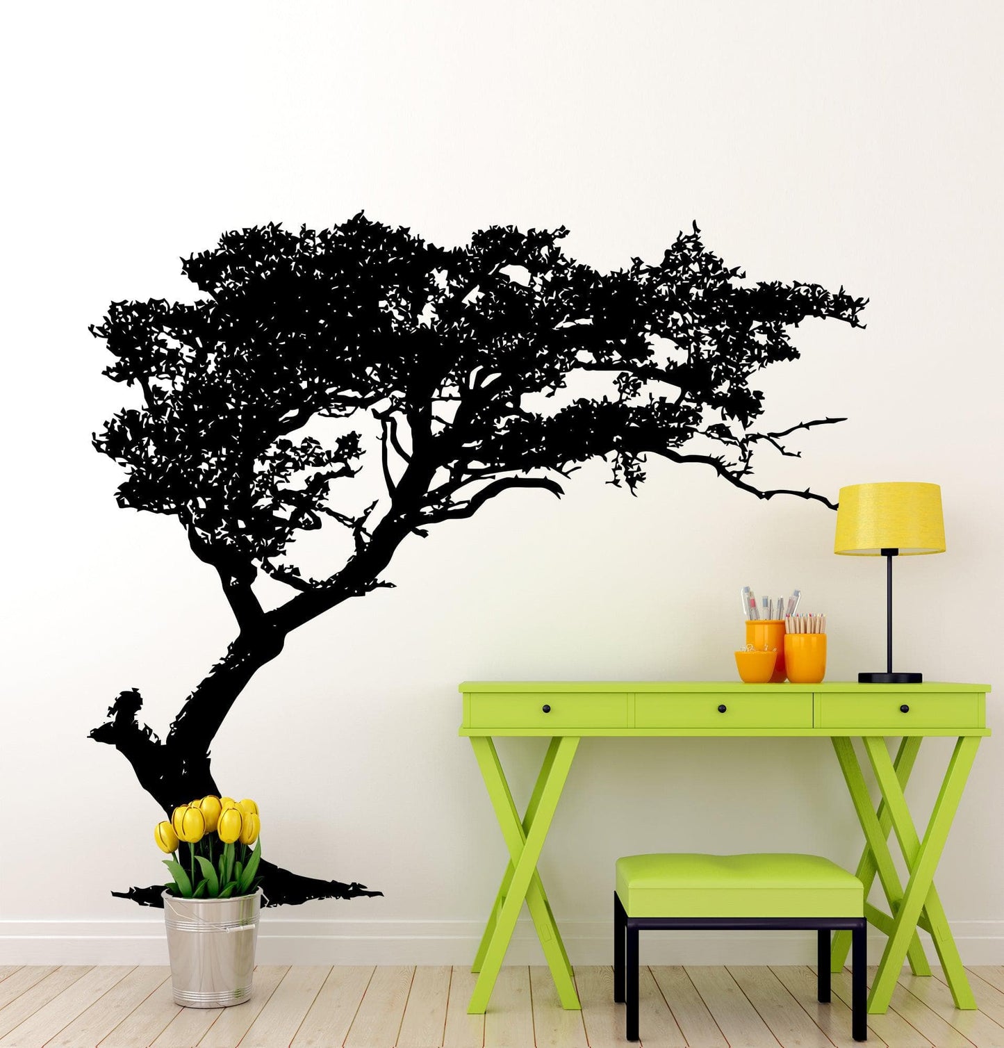 Black tree decal on a white wall next to a yellow desk and chair.