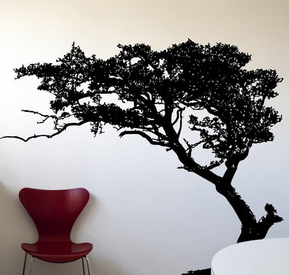 Black tree decal on a white wall next to a red chair.