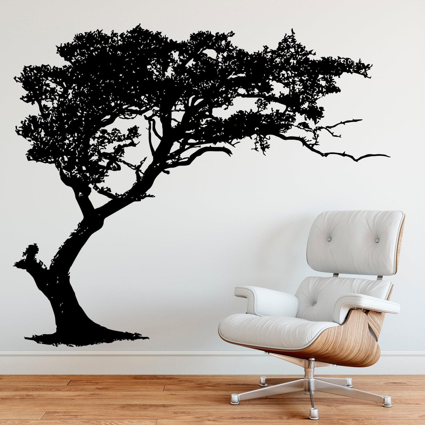 Black tree decal on a white wall next to a white chair.