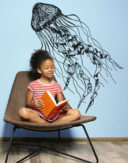 Black jellyfish decal on a blue wall near a child reading on a chair.