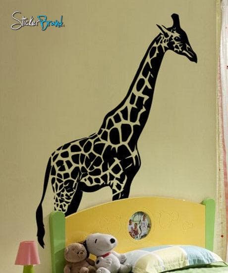 A black decal of a giraffe on a yellow wall in a kid's bedroom.