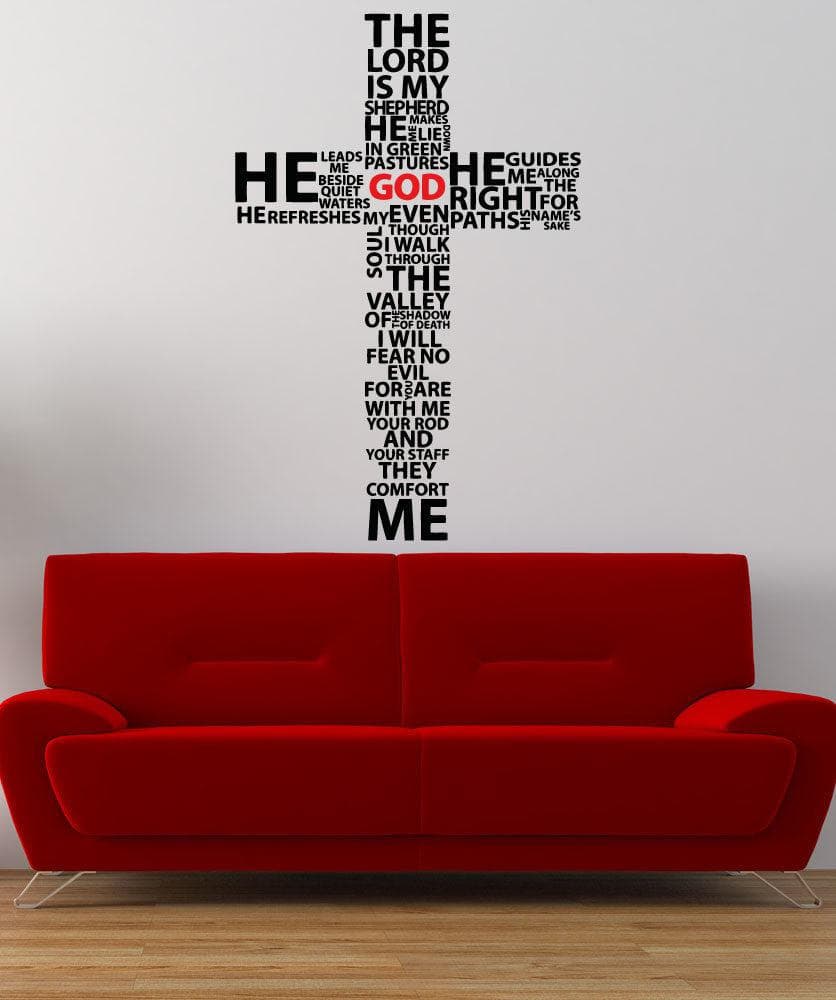 A black decal of a cross with a bible verse on a white wall above a red couch.