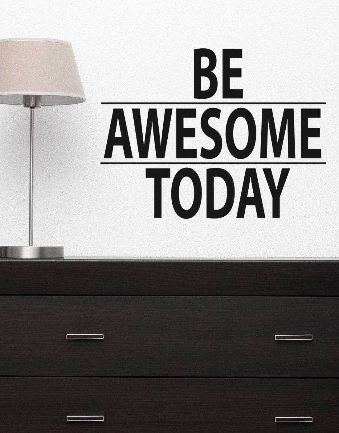 A black text decal saying "BE AWESOME TODAY" on a white wall over a black cabinet.
