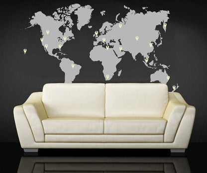 A gray world map decal with white pins on a black background above a white couch.