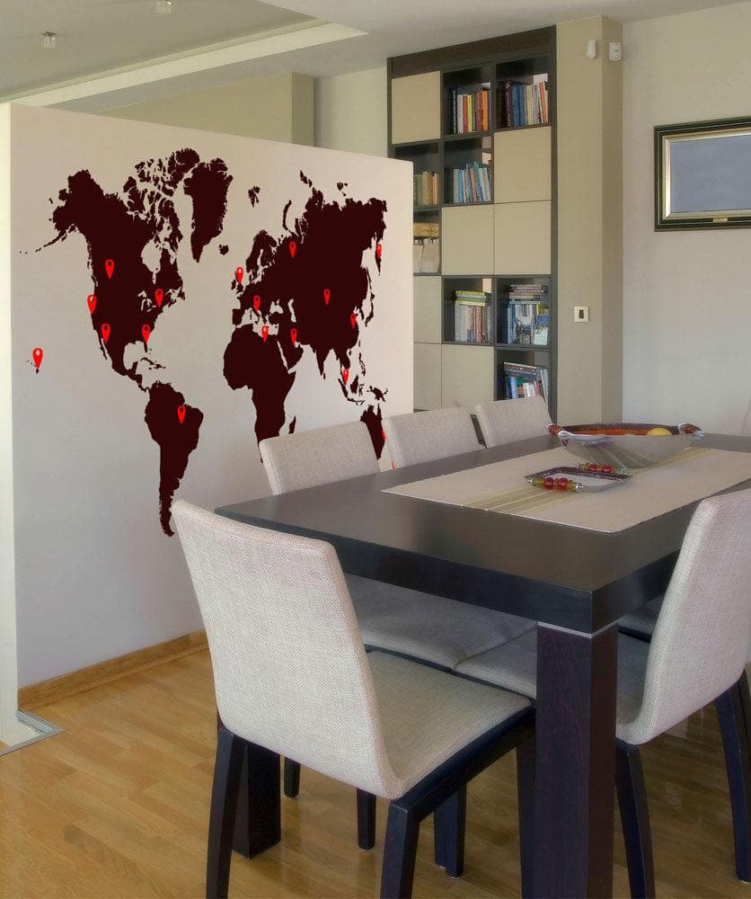 A world map with red pins on various locations against a white wall in a dining room.
