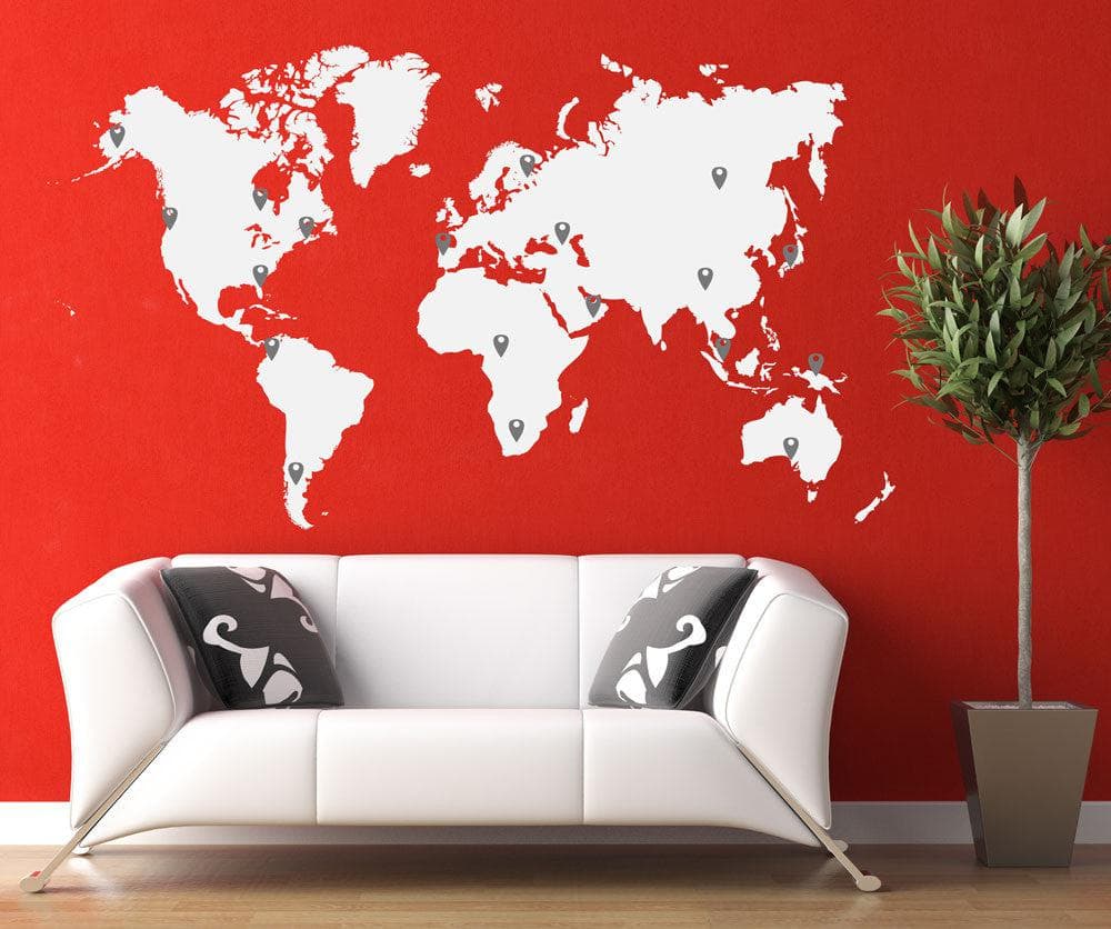 A white world map decal on a red wall above a white couch.
