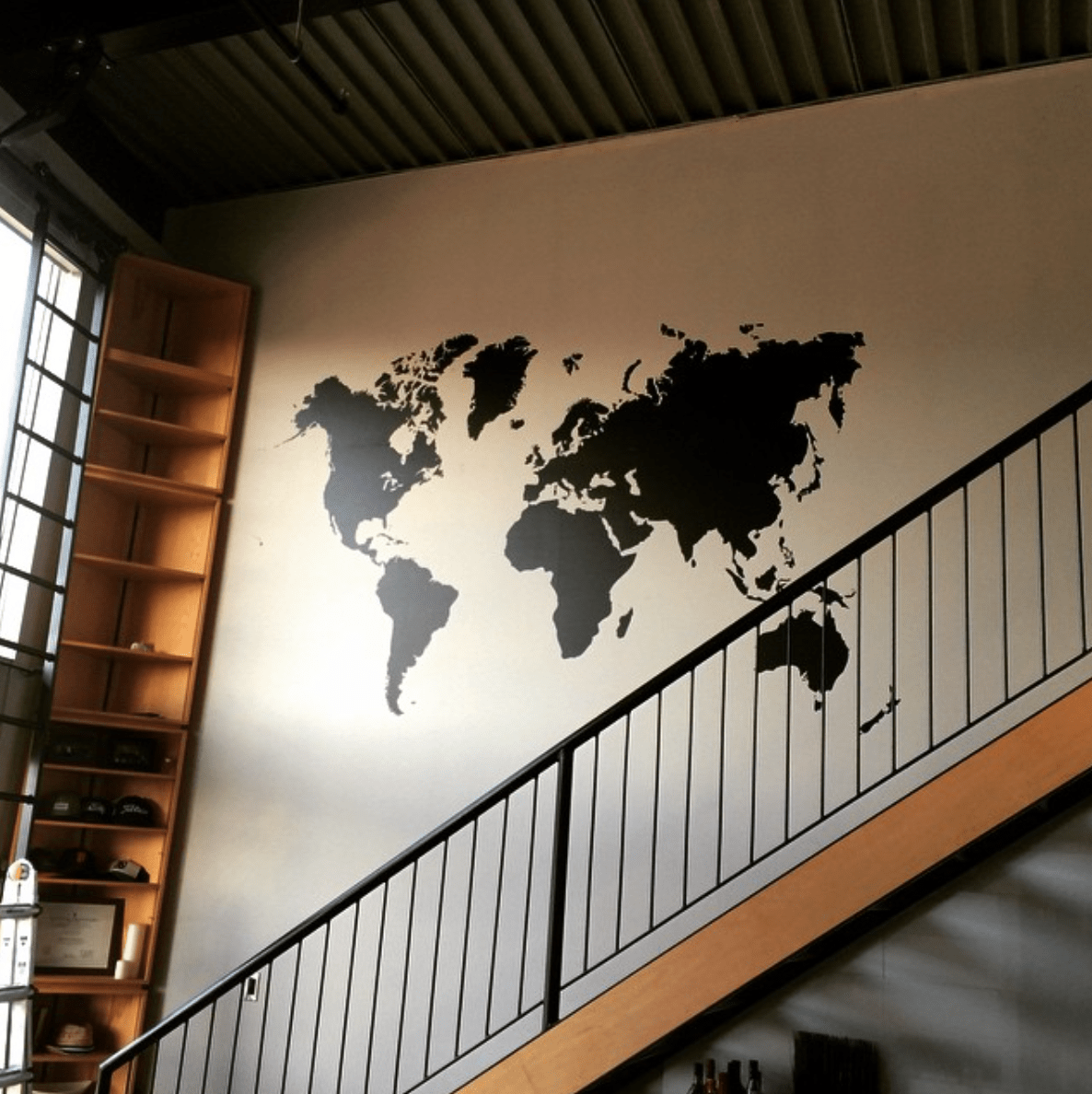 A black world map wall decal on a white wall.