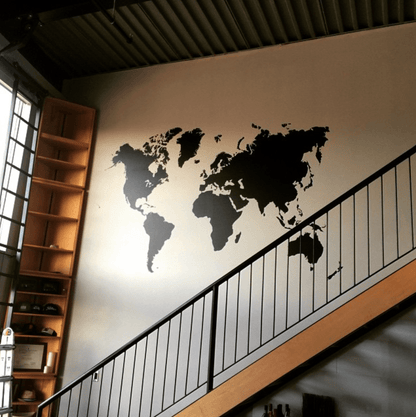 A black world map wall decal on a white wall.