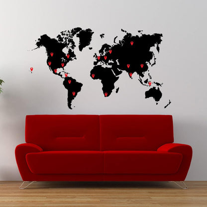 A black world map decal with red pins on a white background above a red couch.