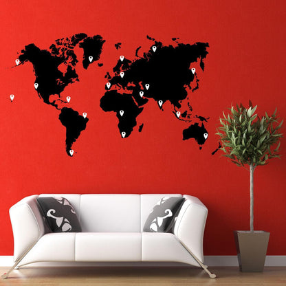 A black world map decal with white pins on a red wall above a white couch.