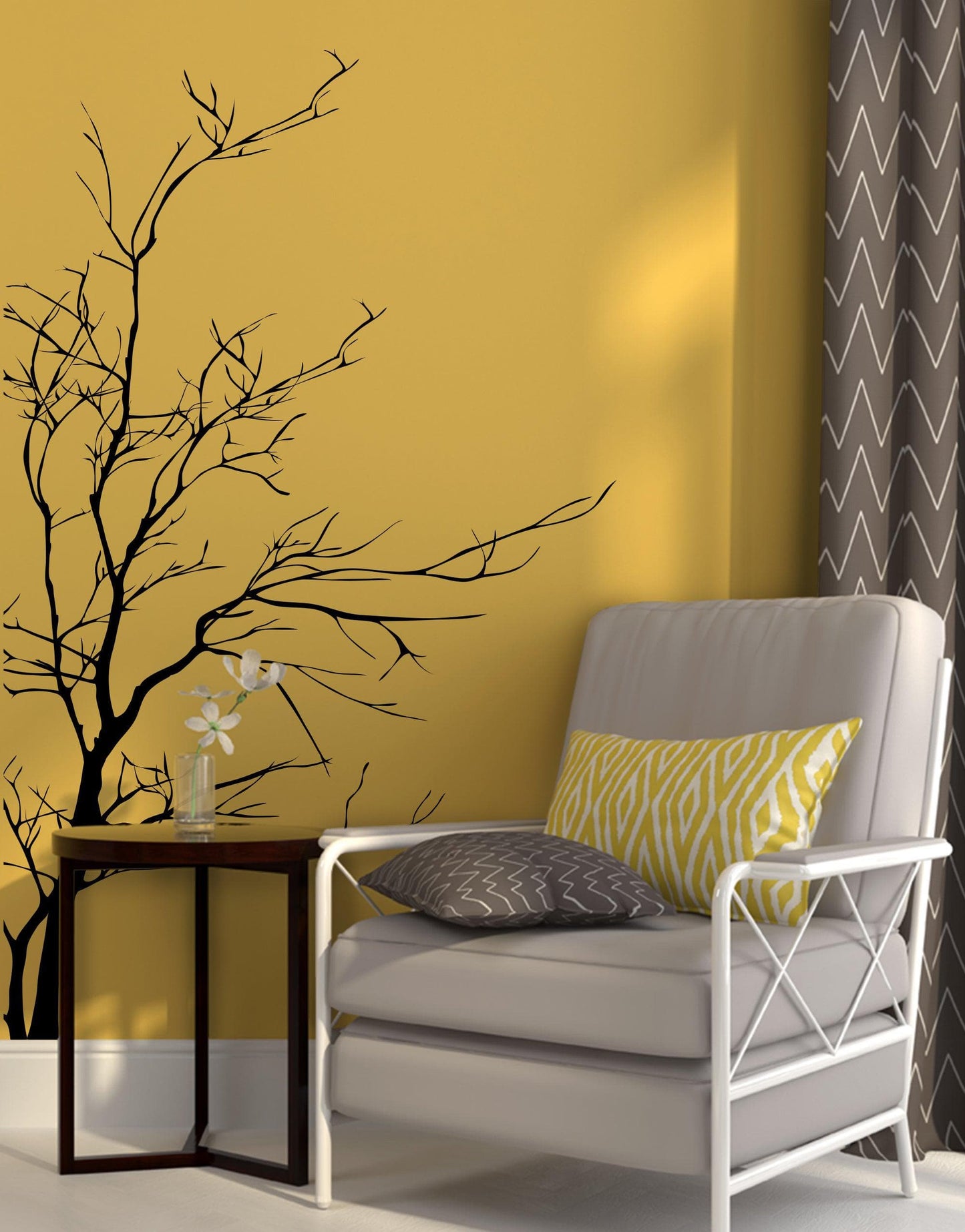 A black tree decal on a yellow wall  near a gray chair.