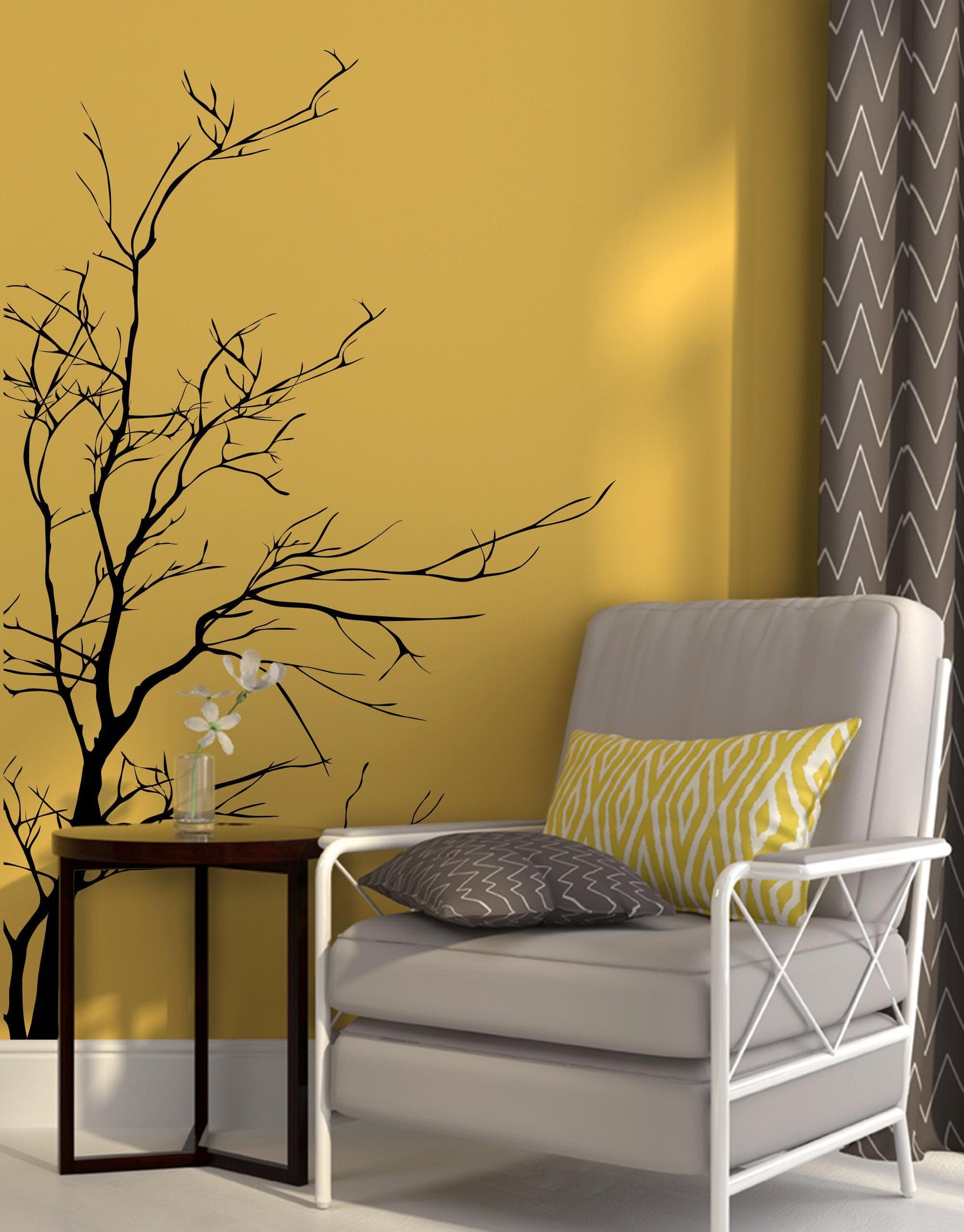 A black tree decal on a yellow wall  near a gray chair.
