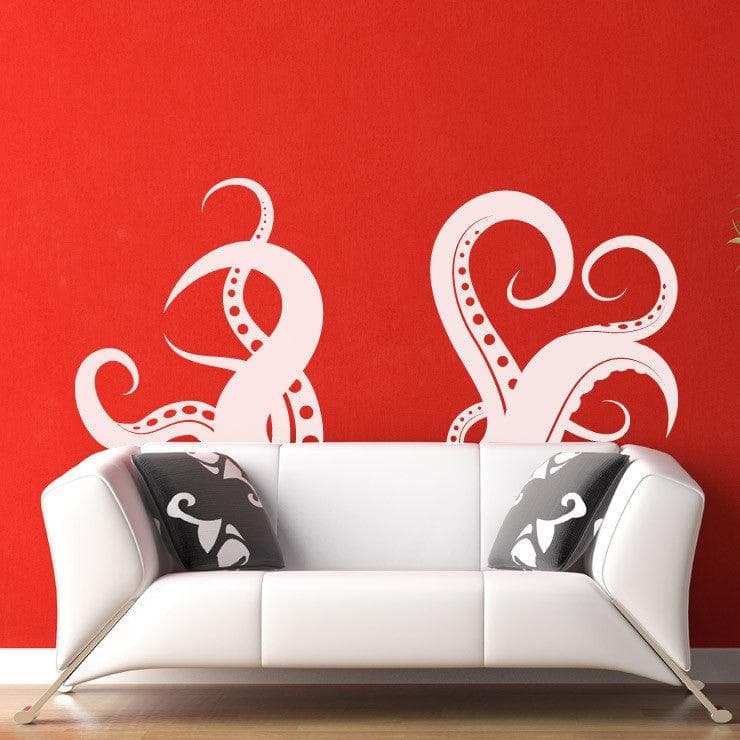 A white octopus tentacle decal on a red wall above a white couch with two pillows.