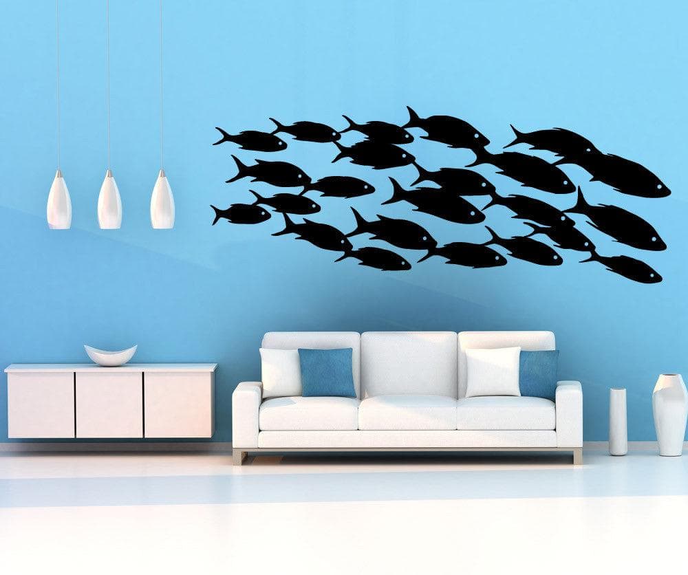 A black decal of a school of fish on a blue wall near a white couch and white lamps.