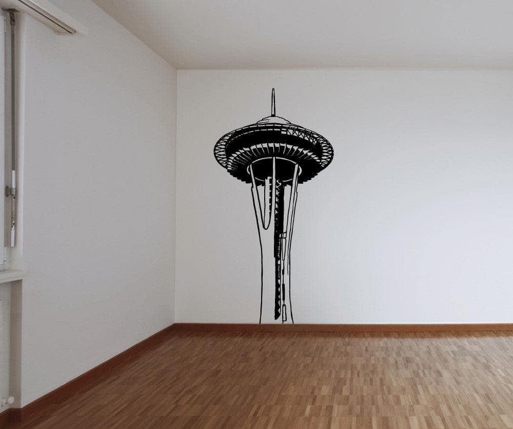 A black decal of the Space Needle building on a white wall in an empty room.